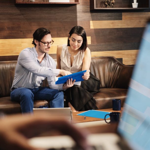 Two people sitting on a couch looking at something.