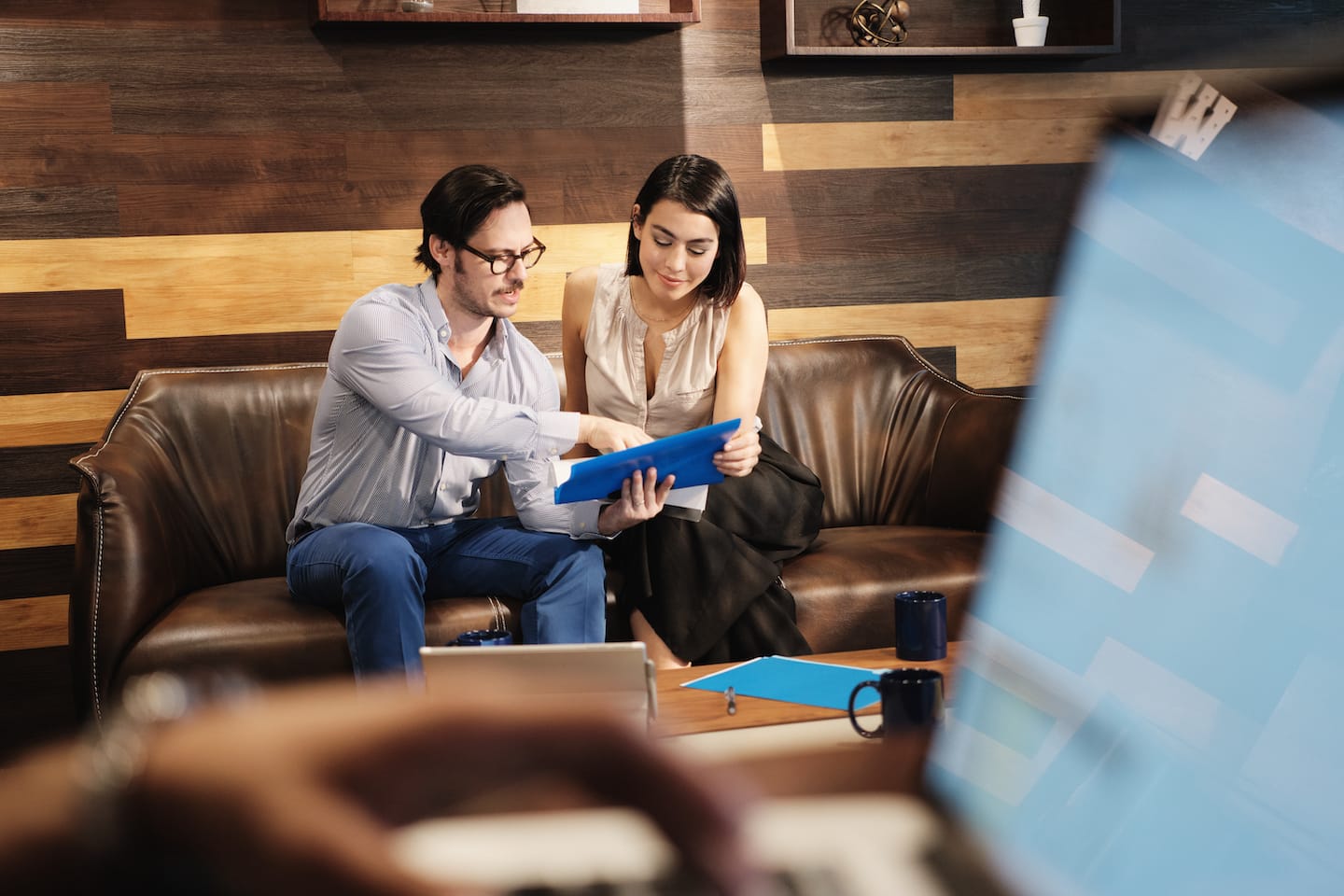 Two people sitting on a couch looking at something.