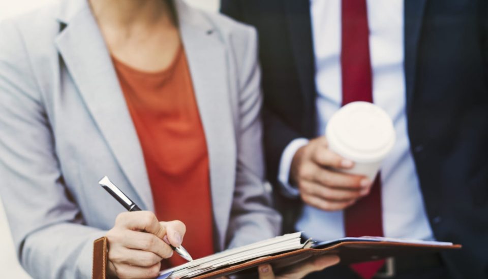 A woman in a gray jacket holding a coffee cup.