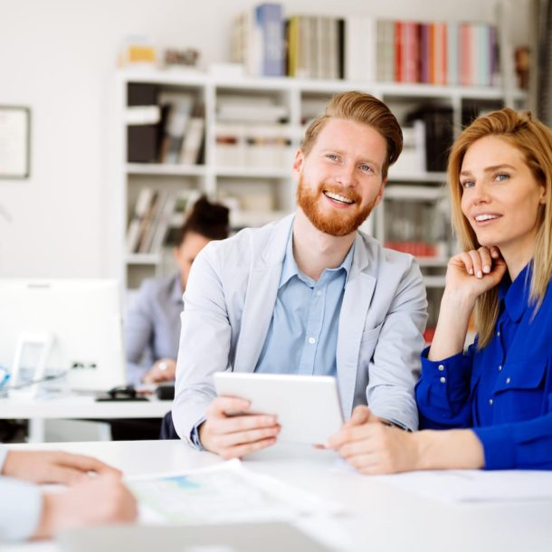A man and woman sitting at a table with papers.