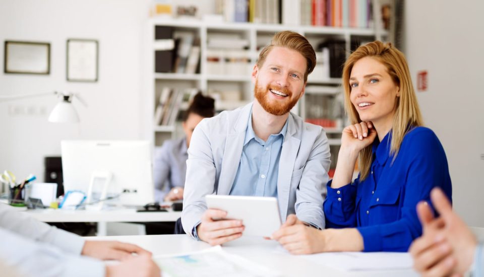 A man and woman sitting at a table with papers.