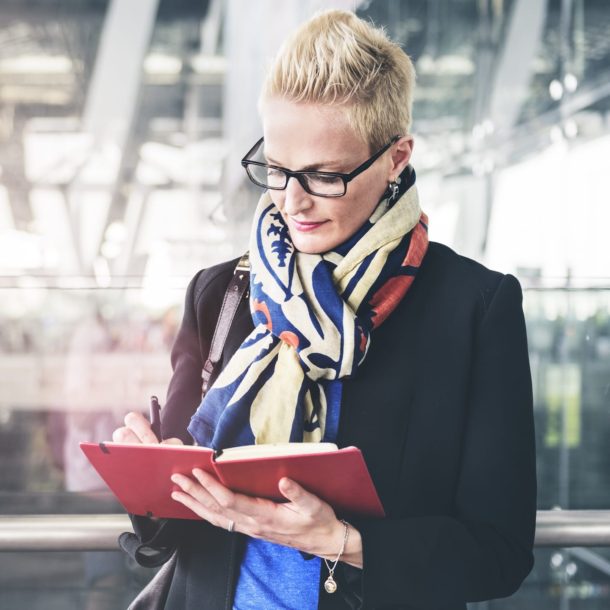 A woman in glasses and scarf reading a book.