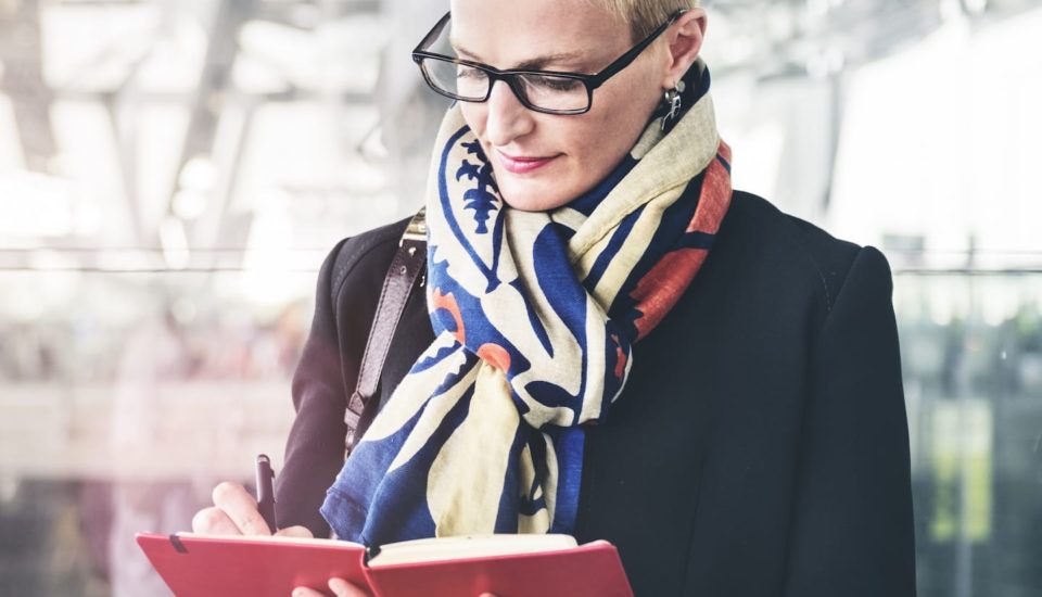 A woman in glasses and scarf reading a book.