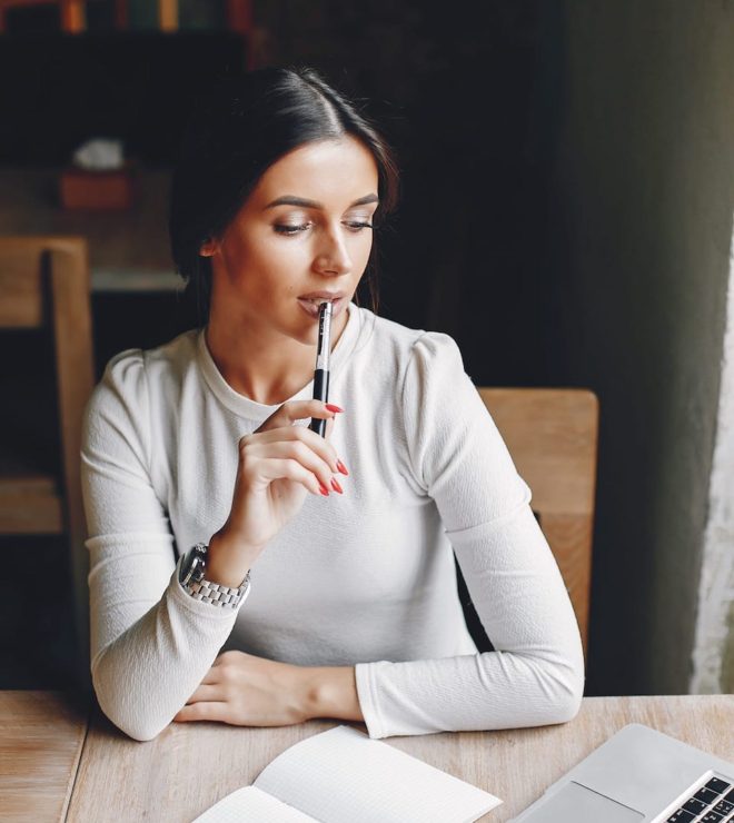 A woman sitting at the table with her hand on her chin.