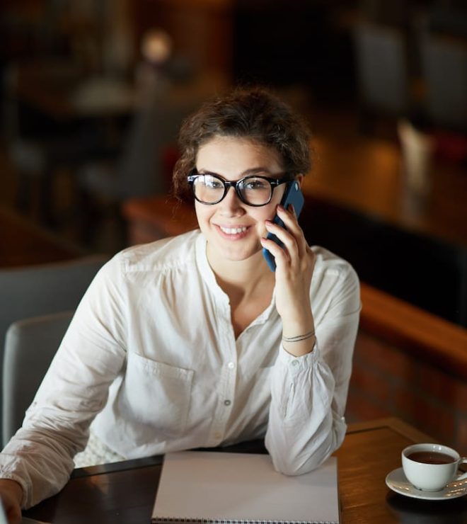 A woman sitting at a table talking on the phone.
