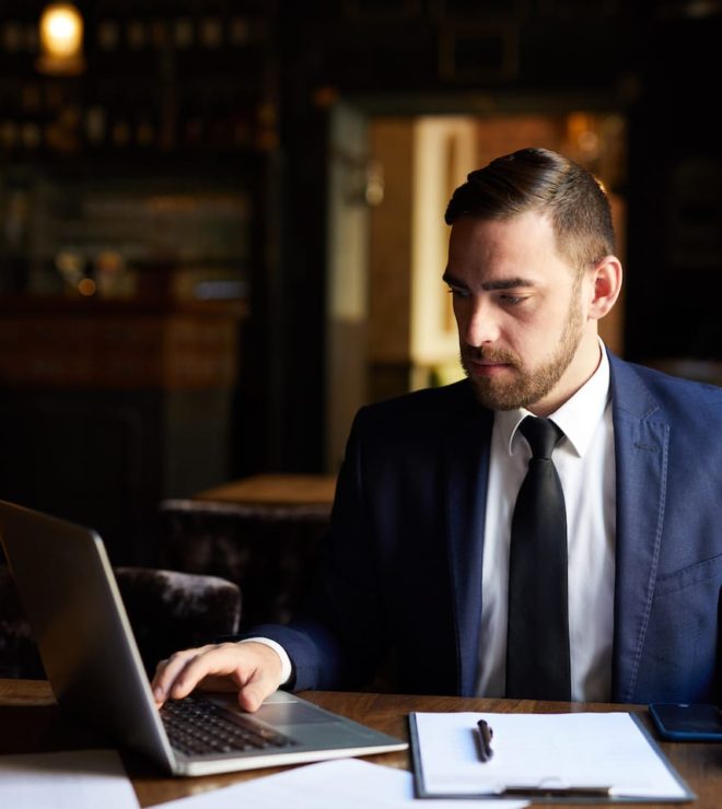 A man in a suit and tie sitting at a table with a laptop.