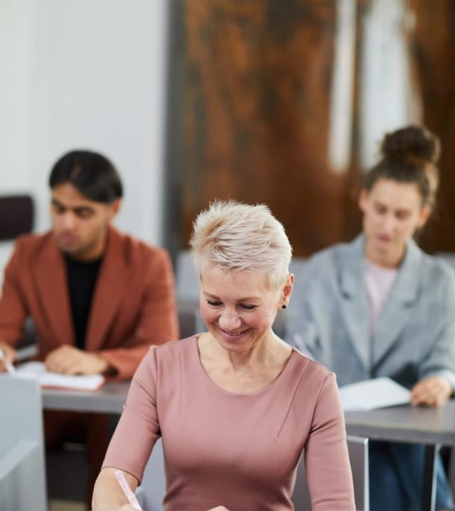 A woman smiles while sitting in front of two other people.